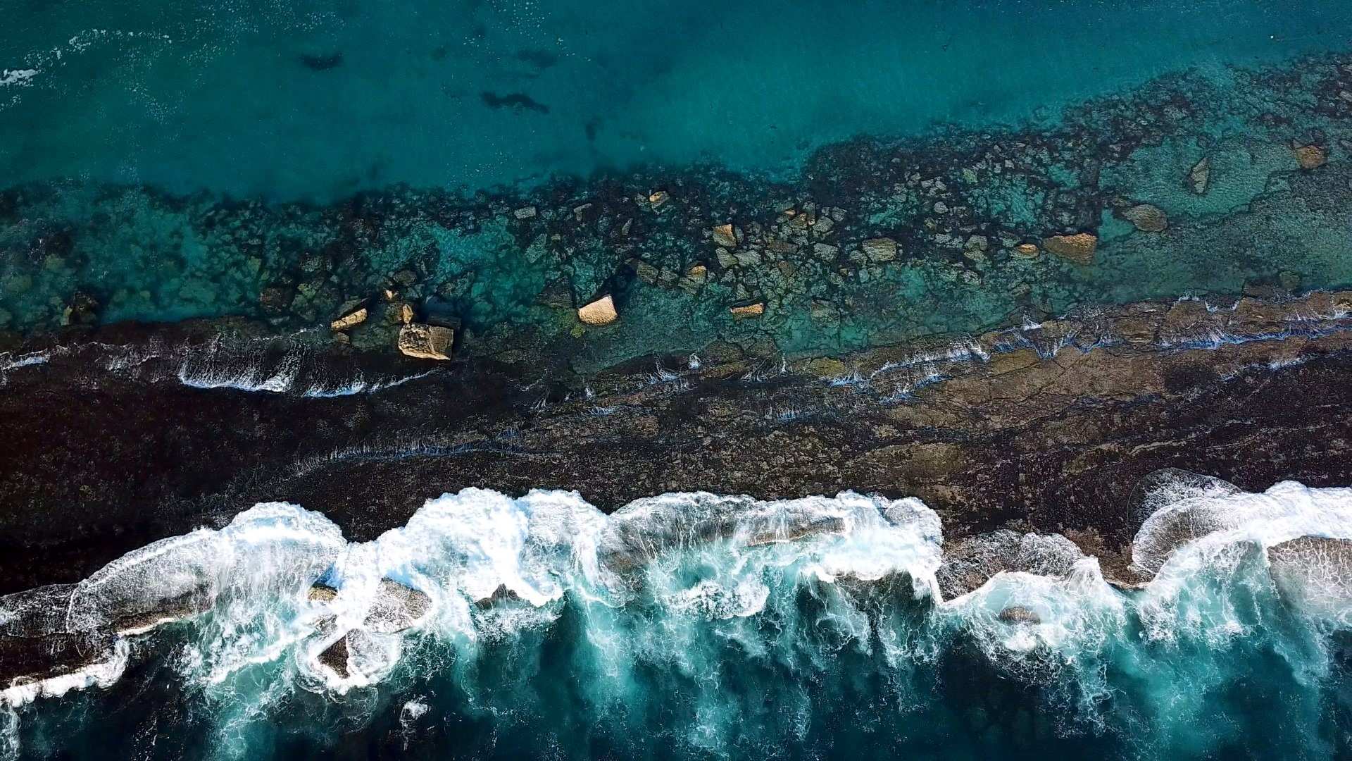 Aerial view of rocky coast and waves.