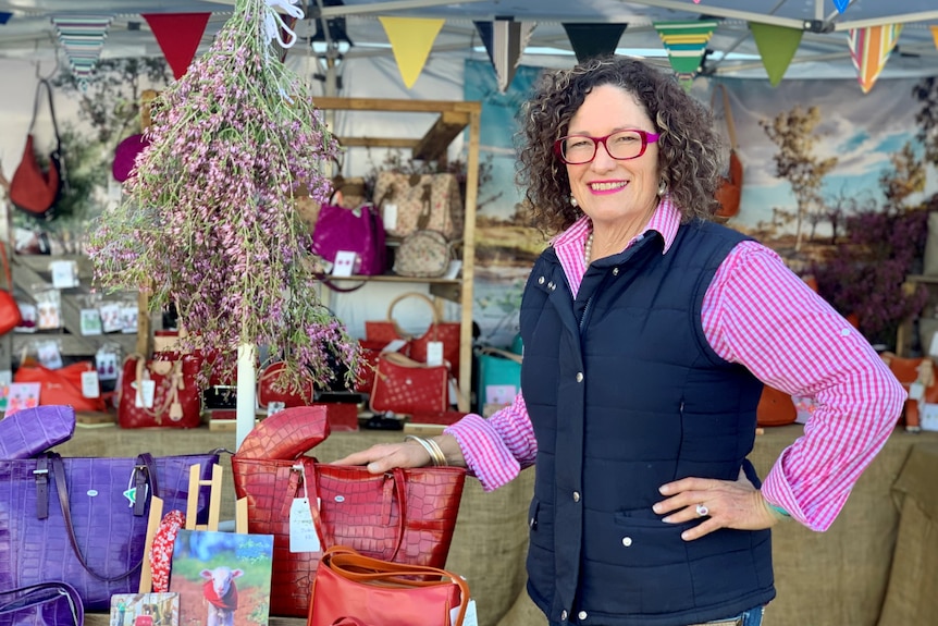 A woman standing in front of handbags. 