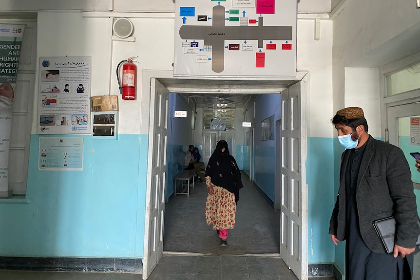 Une femme dans un foulard marche à travers l'entrée d'un hôpital aux murs bleus