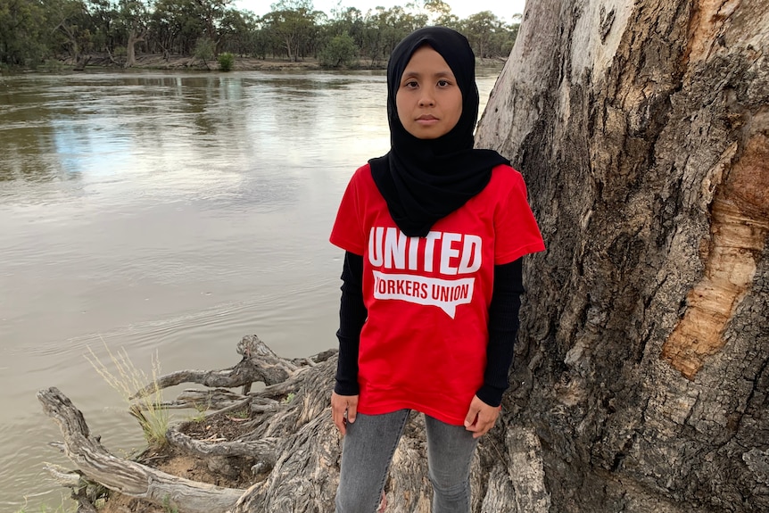 Woman wearing a red United Workers Union shirt and black hijab.