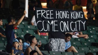 Soccer fans hold a sign which reads "Free Hong Kong Come on City"