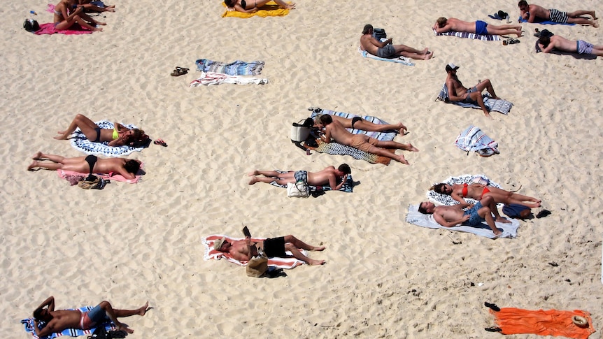 ​​​​​​​ Beachgoers lie on their towels on Tamarama beach during a hot spring day in Sydney, Australia, 2015