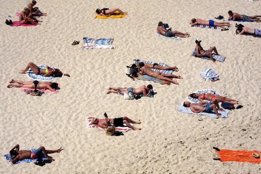 ​​​​​​​ Beachgoers lie on their towels on Tamarama beach during a hot spring day in Sydney, Australia, 2015
