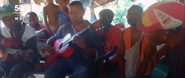 Band sit playing instruments.