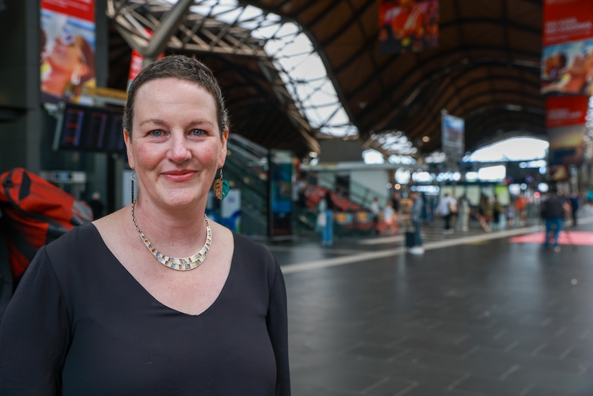 A woman softly smiling at the camera while standing in Southern Cross Station