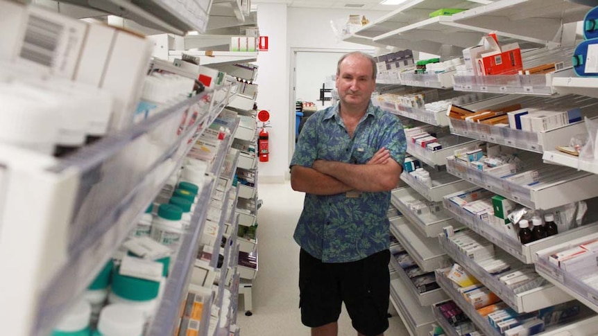Man standing in a hospital pharmacy surrounded by rows of medicine