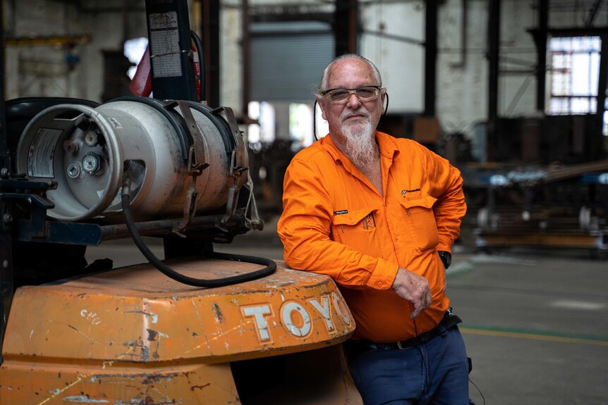 hombre canoso con camisa naranja de alta visibilidad en el taller