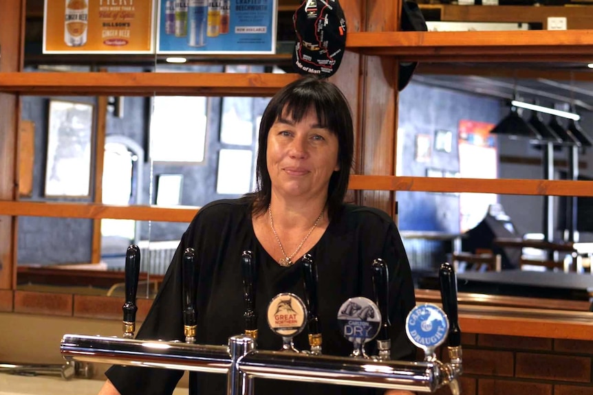 a woman stands behind an empty bar