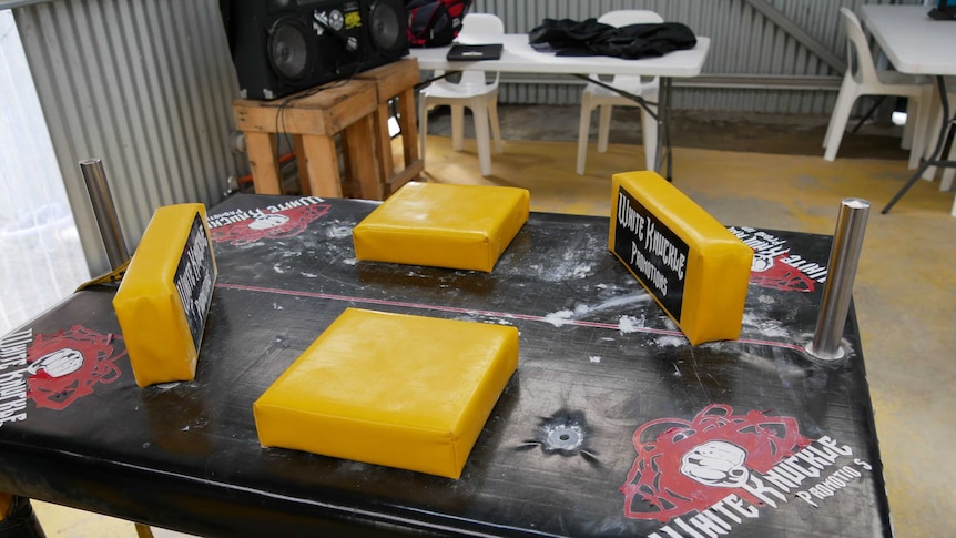 A black table covered in yellow soft pads for arm wrestling competitions.