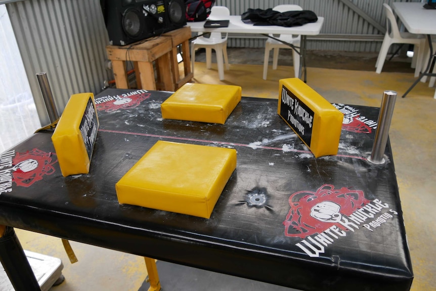 A black table covered in yellow soft pads for arm wrestling competitions.