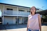 A woman stands in front of her two storey home in Townsville.