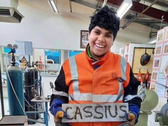 Cassius holds a sign with his name on it that he welded