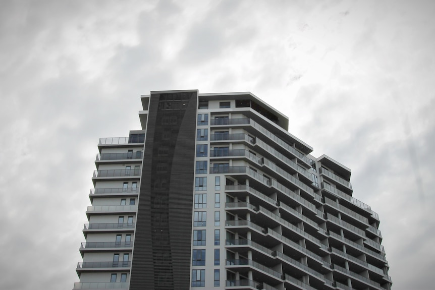 A high rise building in the foreground of a stormy cloudy day