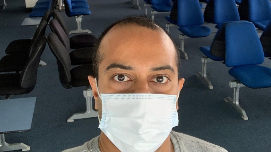 Kaushik Sridharat wearing a face mask with an  empty airport in the background.