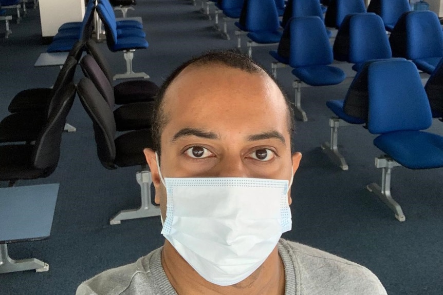 Kaushik Sridharat wearing a face mask with an  empty airport in the background.