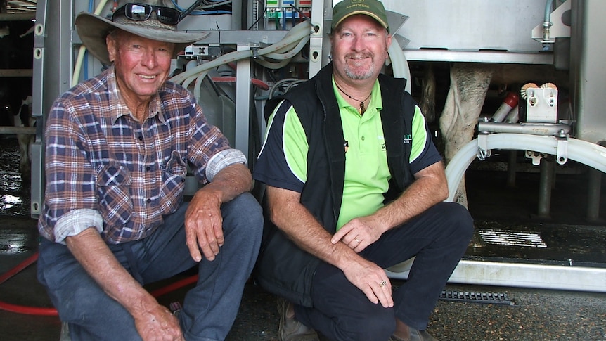 Darrell and Greg Dennis pose in front of their robotic milking machine.