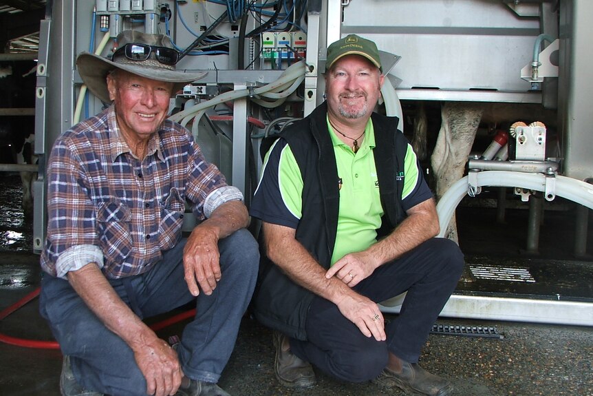 Darrell and Greg Dennis pose in front of their robotic milking machine.