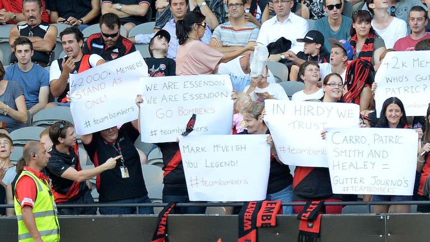 Essendon supporters hold up signs to show their support during a preseason cup match.
