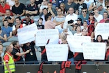 Essendon supporters hold up signs to show their support during a preseason cup match.
