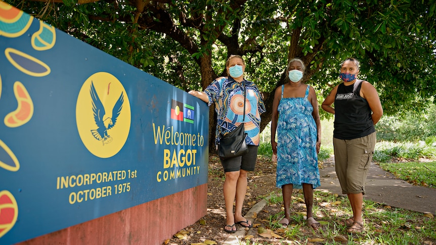 Marita Mummery, Valemina White, and Natalie Howard standing next to the Bagot community entrance sign.