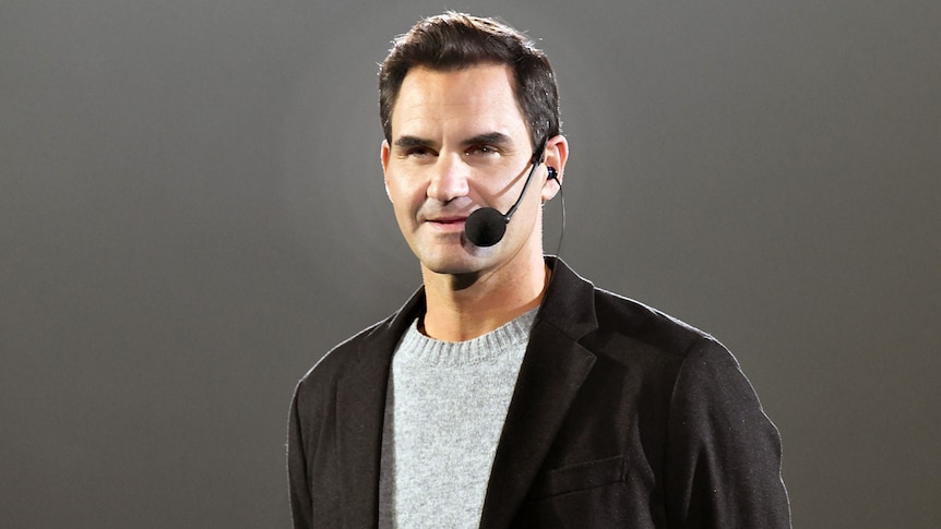 Roger Federer stands looking at an audience wearing a headset microphone during a public Q and A.