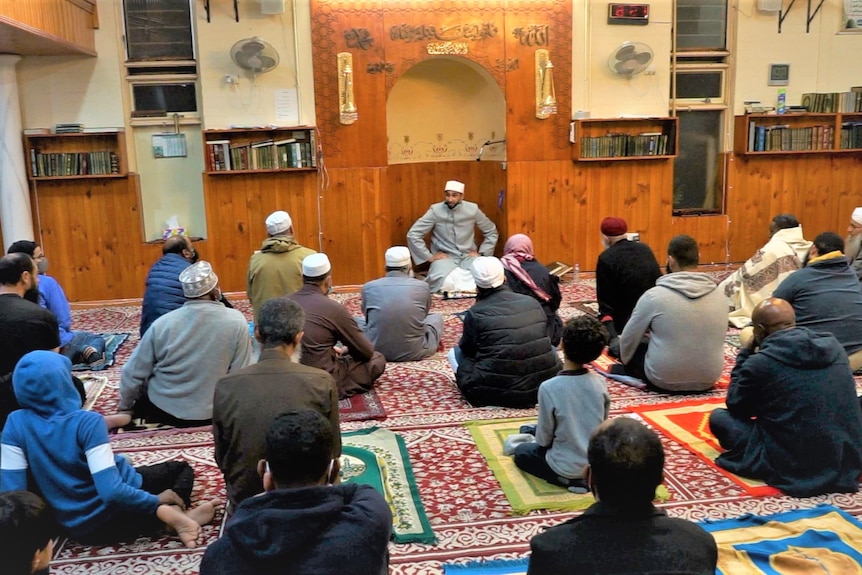 A group of men indise a mosque sitting on the floor