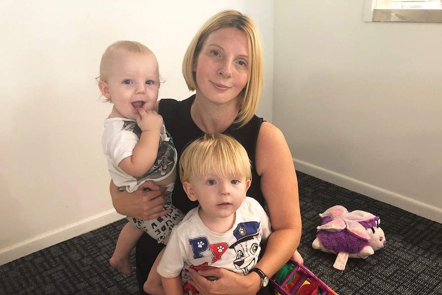 Alison French and her sons Zack and Aaron sit on a floor with toys at an evacuation centre.