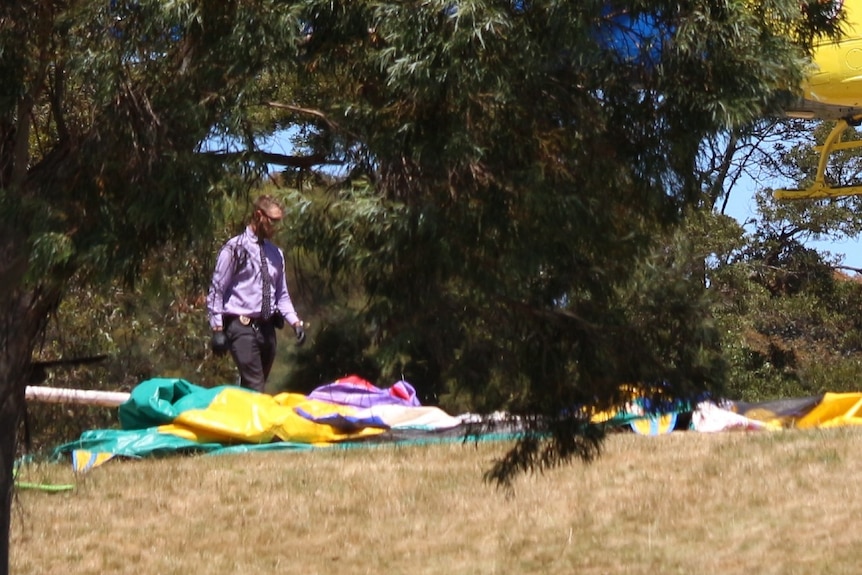 A man walks past colourful plastic under a tree