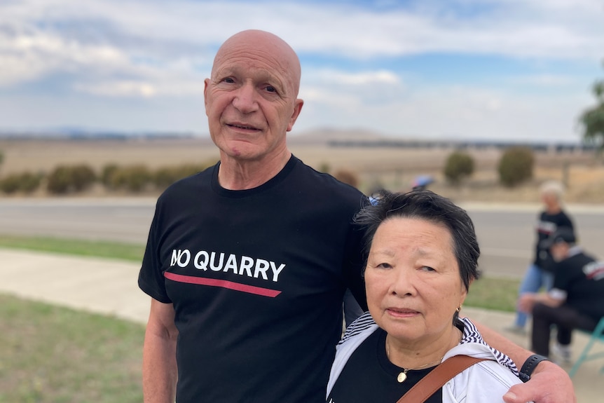A man — wearing a 'no quarry' shirt — and woman with their arms around each other. 
