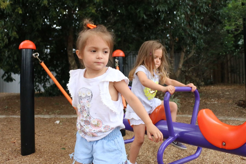 Four year old twins Eva and Sofia play on the seesaw