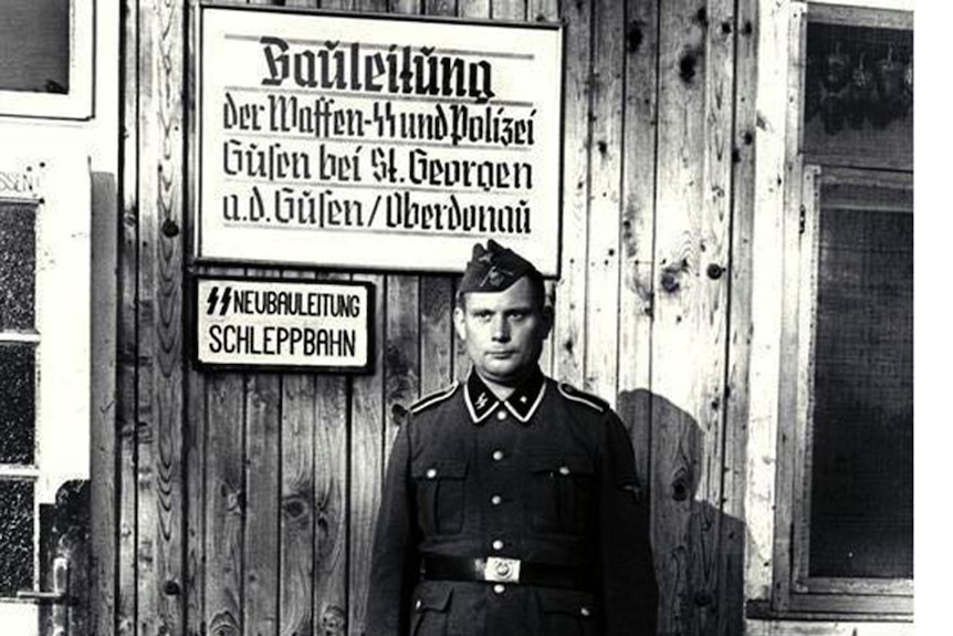 A Nazi SS officer stands in front of a sign at the Mauthausen concentration camp