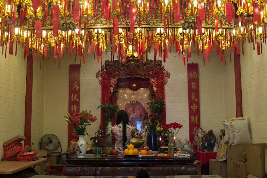 Alter in temple with red lights and prayers hanging from the ceiling