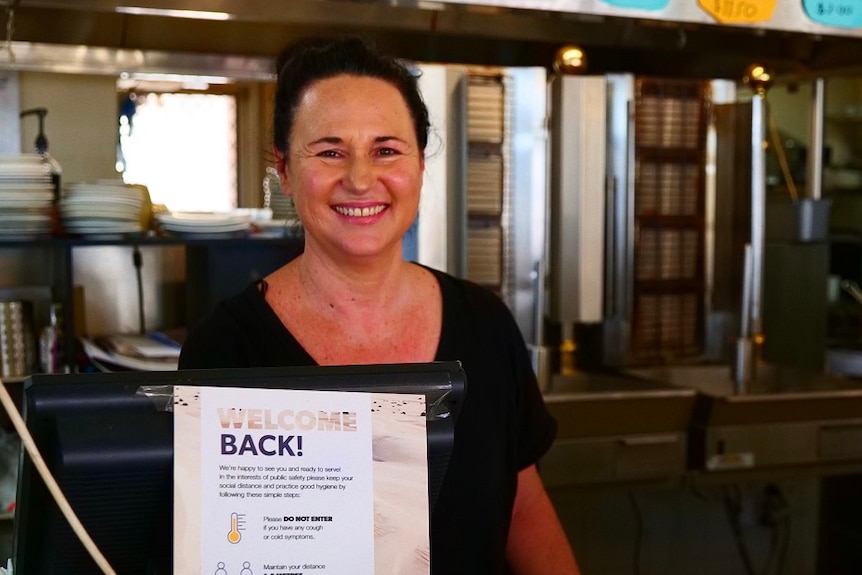 Woman smiling, standing behind count in a cafe.