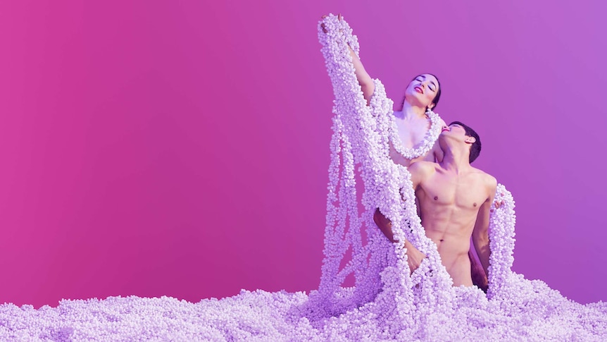 Two naked people shrouded in strings of pearl-like beads.
