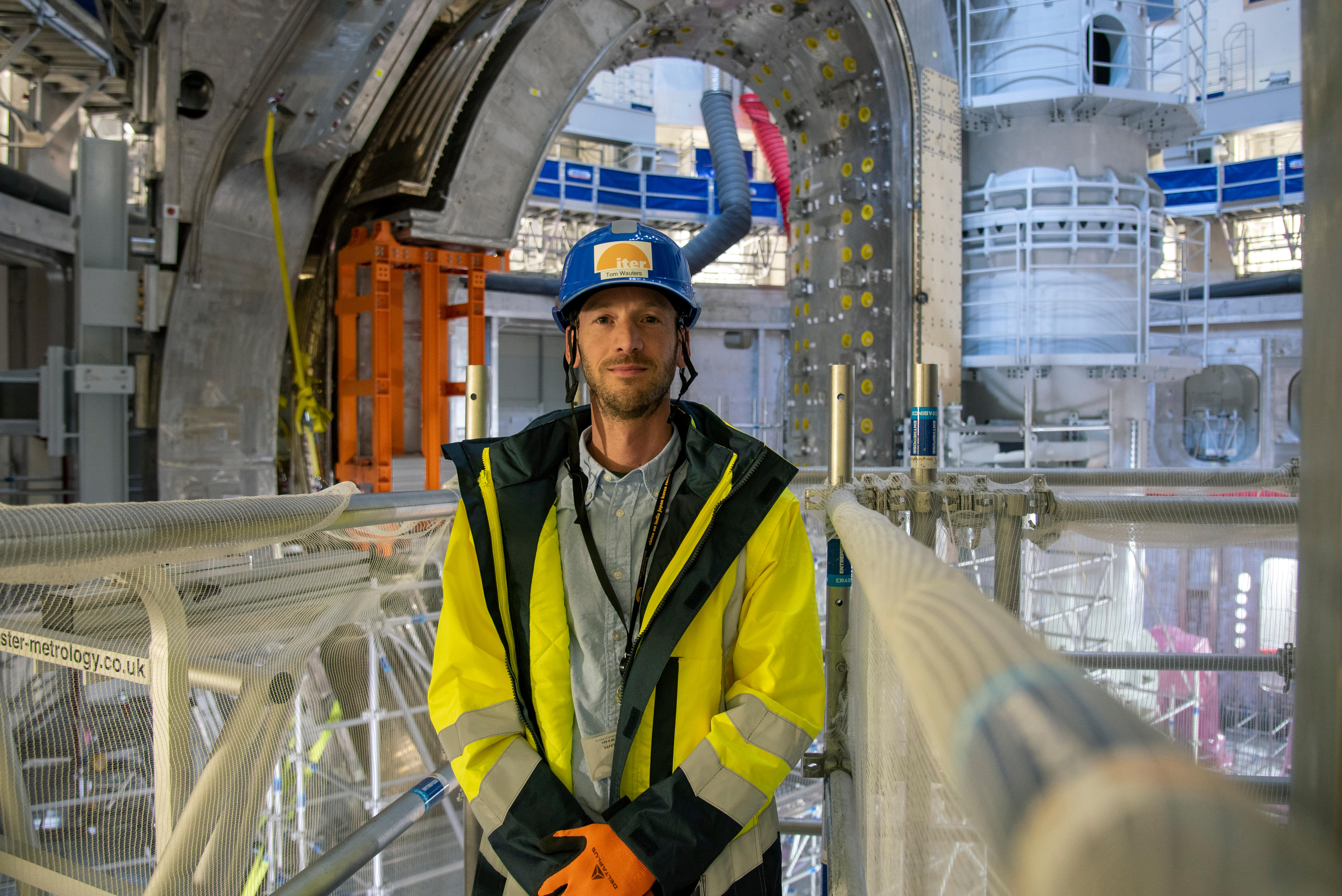 Tom Wauters in hard hat and high vis inside the tokamak with the module framing him and the central pillar behind his shoulder