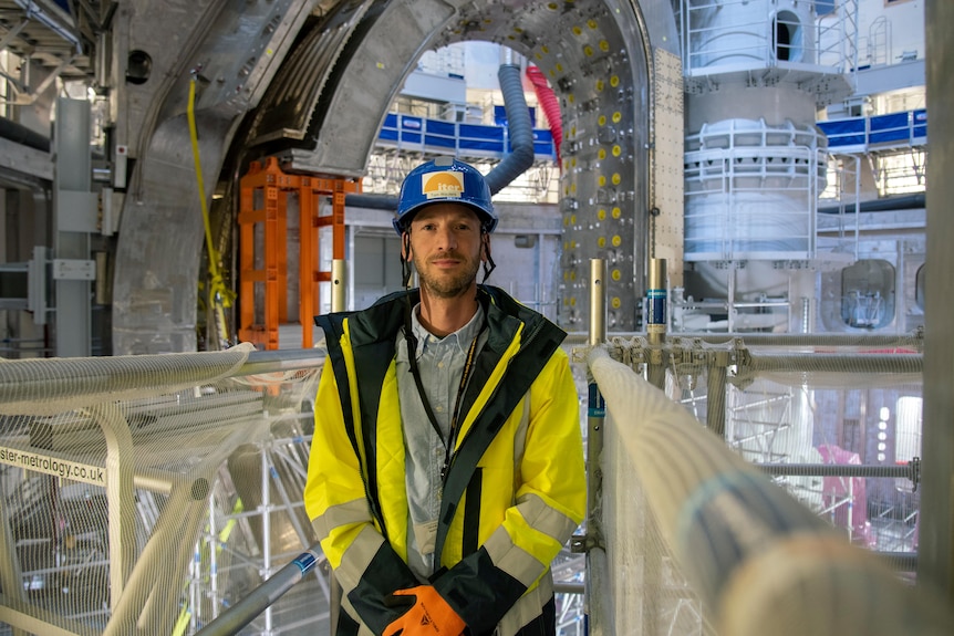 Tom Wauters in hard hat and high vis inside the tokamak with the module framing him and the central pillar behind his shoulder