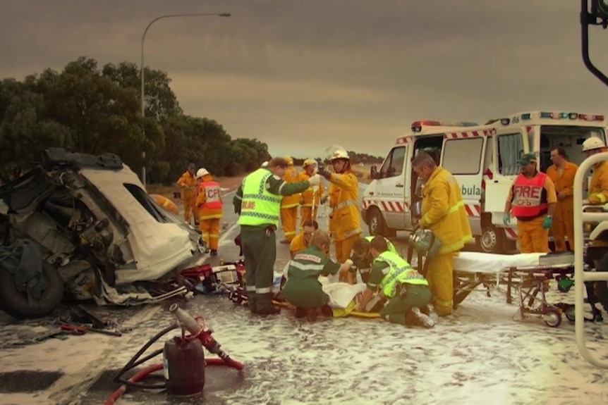Emergency personnel work at a vehicle crash site