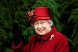 女王身穿红色外套，戴着红色礼帽，向镜头亲切地挥手