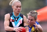 Erin Phillips looks ahead while carrying the ball as Ella Roberts lunges to tackle her