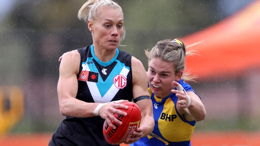 Erin Phillips looks ahead while carrying the ball as Ella Roberts lunges to tackle her