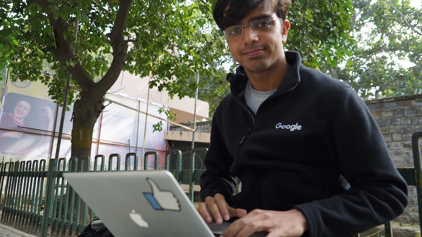Indian Institute of Technolgy student Raghav Sarin sits on a bench under a tree nursing a laptop