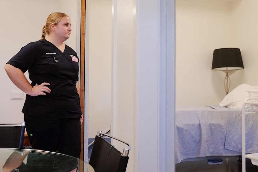 Nurse standing in the doorway of a hospital room.