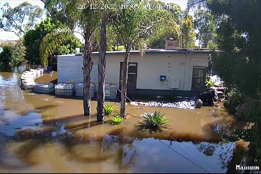 A security camera vision showing a makeshift levee built around a house but water has flooded the home