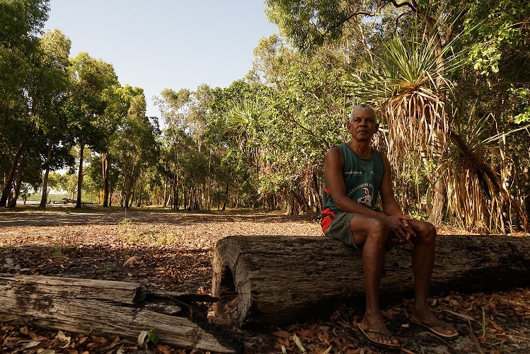 John Rioli sits on a log in Pirlangimpi.
