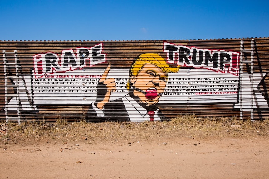 A spray painted mural of Donald Trump with a red gag ball in his mouth and 'Rape Trump' over his head.