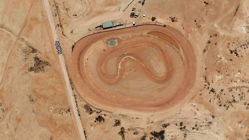 An aerial shot shows Coober Pedy's red dirt old race track from above.