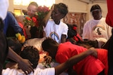 A child wipes tears from his face as others hug the coffin of Mr E Perdjert
