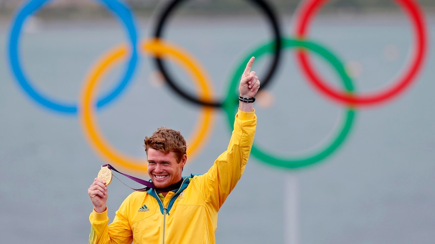 Tom Slingsby holds the gold medal he won in the men's Laser class sailing competition.