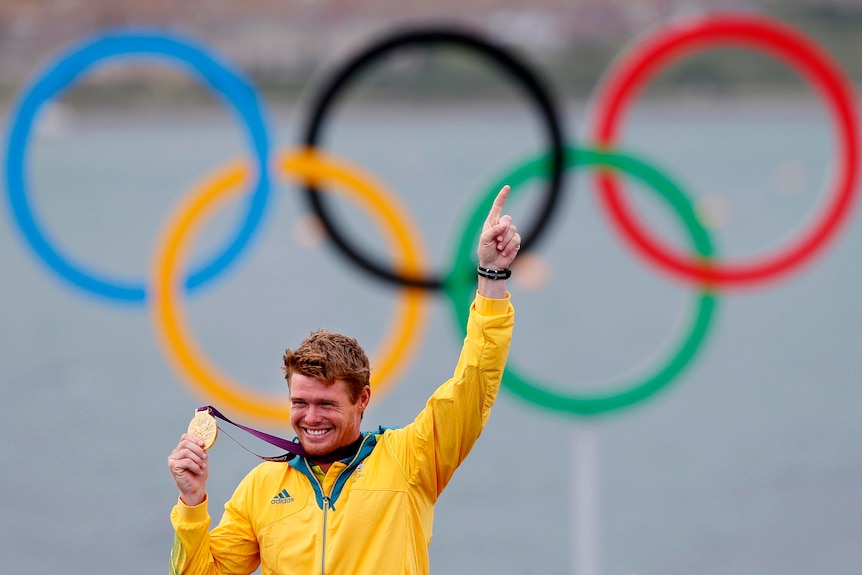 Tom Slingsby holds the gold medal he won in the men's Laser class sailing competition.