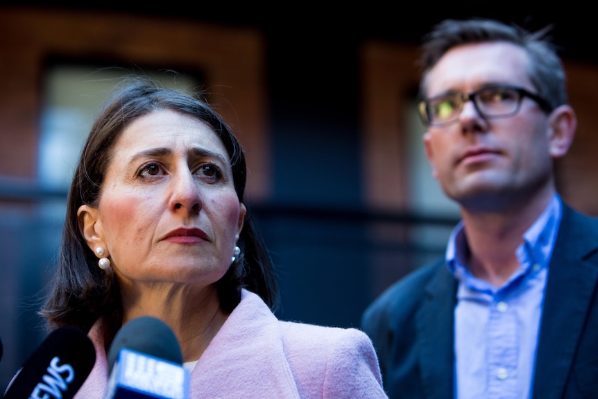 a woman looking stern standing next to a man wearing glasses